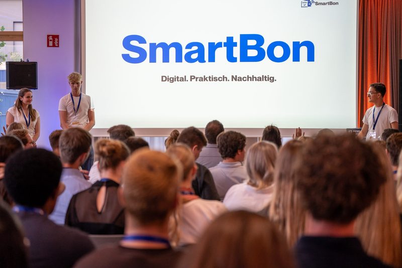 Das SmartBon-Team pitcht auf einer Bühne vor Publikum